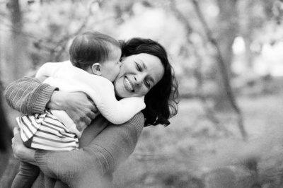 A mother snuggles their child in the park.