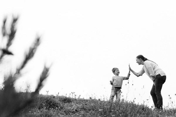 A mother and son high five each other in a field.