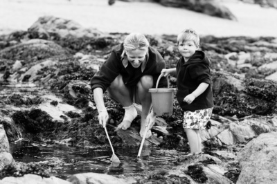 A mother and her son go rockpooling with a net and bucket.