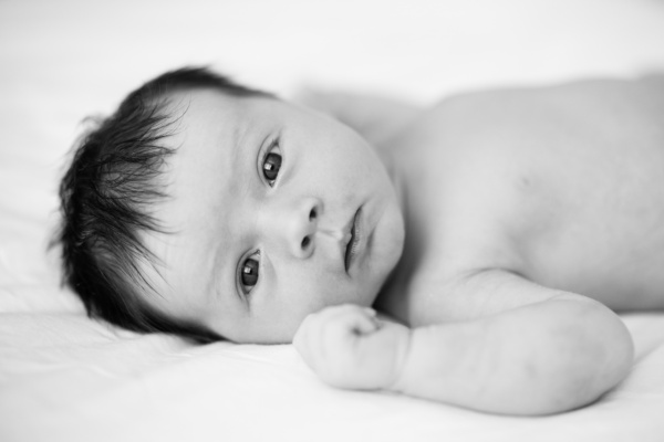 A blak and white portrait of a newborn with their eyes open.