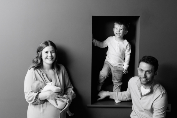 A newborn, its brother and parents pose together for a family portrait.