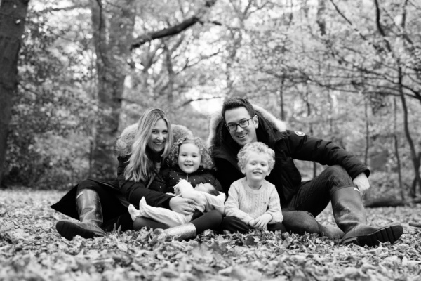 Siblings and their parents welcome a newborn in a portrait shoot in autumn leaves.