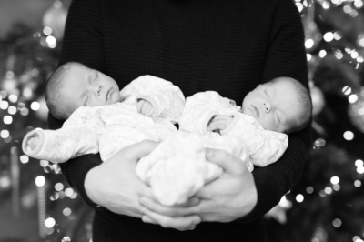 A father holds his sleeping newborn twins.