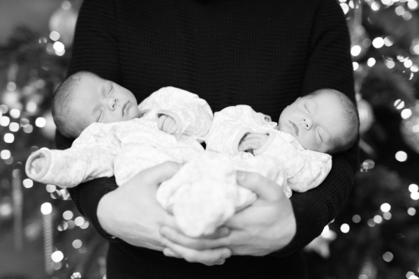 A father holds his sleeping newborn twins.