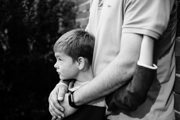 A parent puts his arms around their child.