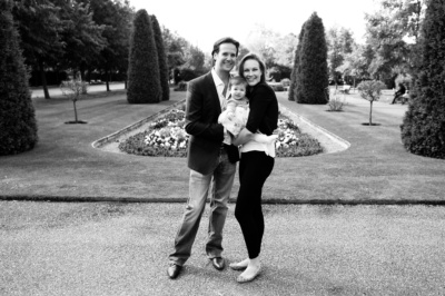 Parents and their baby in formal gardens.