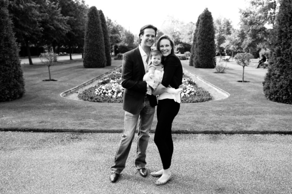 Parents and their baby in formal gardens.