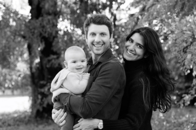 Parents hug their baby in a park during a London portrait shoot.