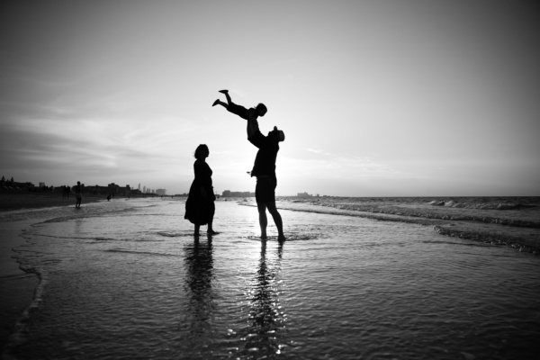 Parents and their baby play at the beach.