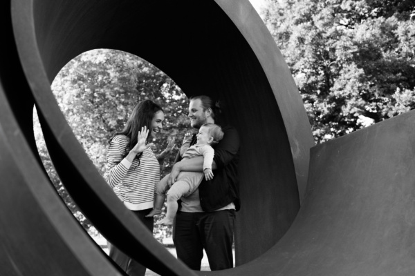 Parents and their baby framed by a metal sculpture loop.