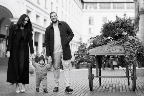 Parents and their baby walk through Covent Gardenat Christmas time.