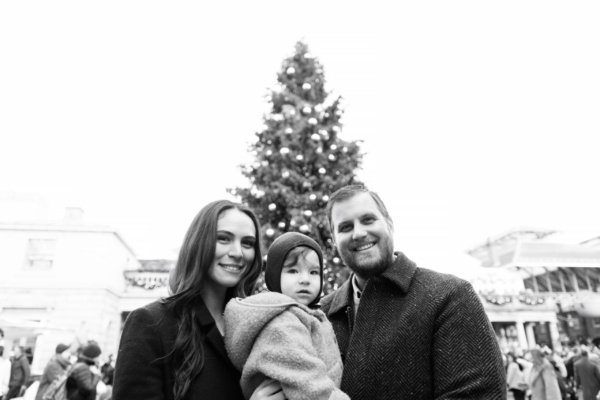 Parents and their baby stand in front of a Christmas tree in London's Covent Garden.