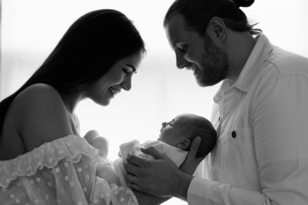 Parents cradle their newborn against a newborn.