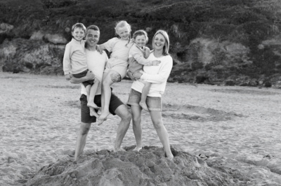 Parents hold their three children in a beach portrait.