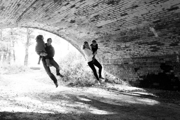 Parents jump in a brick arch with their children.