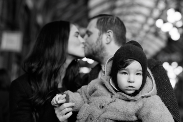 Parents kiss while their baby looks at family photographer Helen Bartlett.