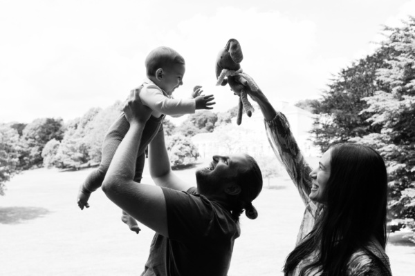 Parents lift up their baby and their toy.