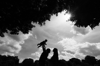 Parents lift up their baby against the sky, creating a silhouette.