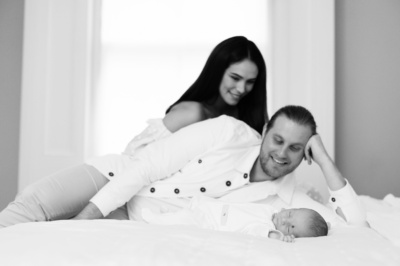 Parents look at their newborn baby on their bed.