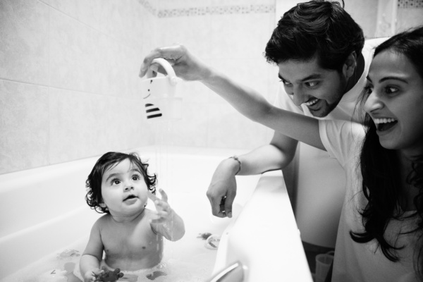 Parents play games with their baby in a bath.