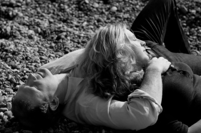 Parents relax on a pebble beach.