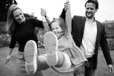 Parents swing their child in gardens.