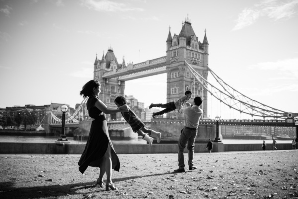 Parents swing their children in the air near Tower Bridge in a portrait shoot while they visited London and its landmarks.