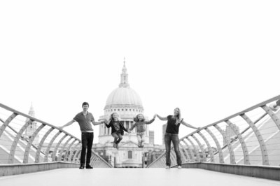 Family of four walk across the Millennium Bridge, London, in front of St Paul's Cathedral. This is one of a series of vacation portraits.