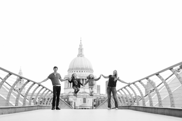 Family of four walk across the Millennium Bridge, London, in front of St Paul's Cathedral. This is one of a series of vacation portraits.