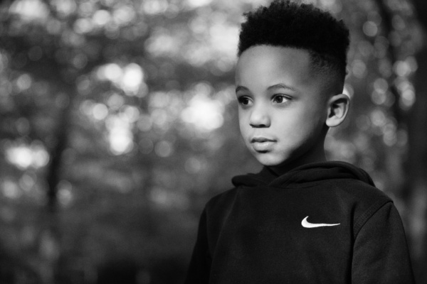 Black and white portrait of a boy with trees in the background.