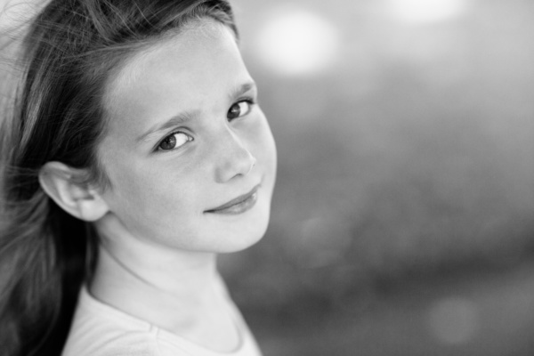 A black and white portrait of a smiling girl.