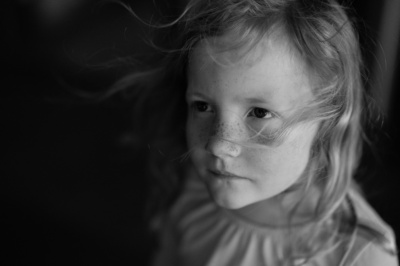 A quiet girl against a dark background.