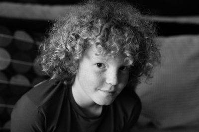 A quietly smiling teenager looks at the camera in a black and white portrait.