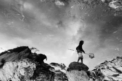 Reflection of a child fishing with a net.