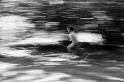 A teenager speeds along under trees.