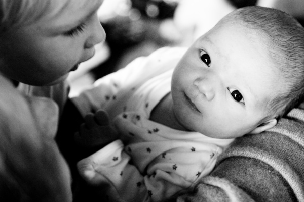 Sibling looks at new baby in a family portrait shoot.