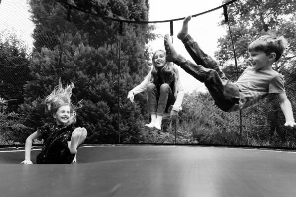 Siblings bounce on trampoline.