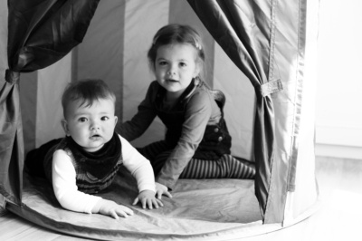 Siblings play in a wendy house together.