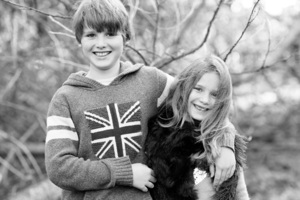 A black and white portrait of siblings in woodland.