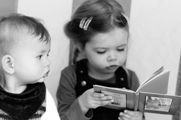 Siblings read a book together.