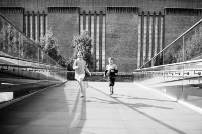 Siblings run across the Millennium Bridge in London.