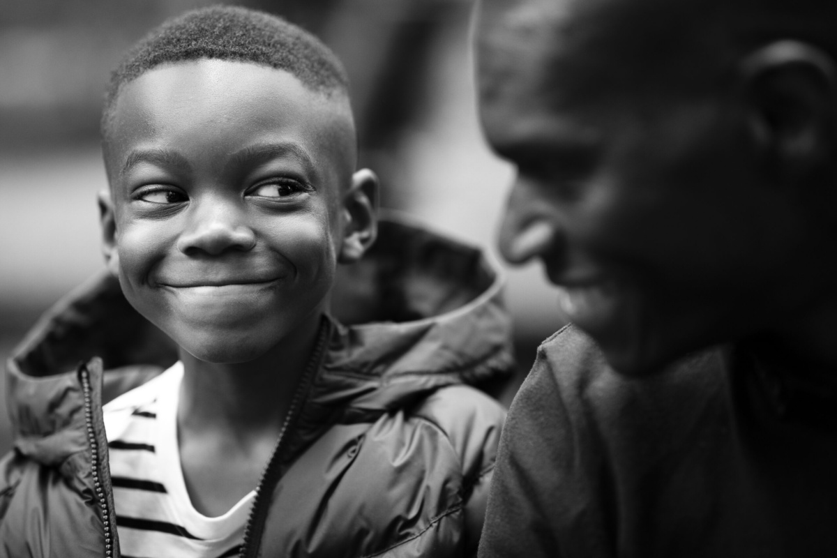 Siblings smile at each other in a black and white portrait.