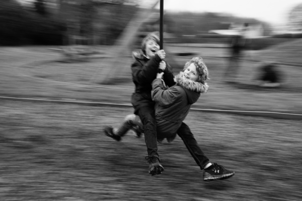 Siblings swing together in a field.