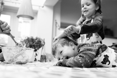 Sister rolls brothers head with rolling pin while baking.