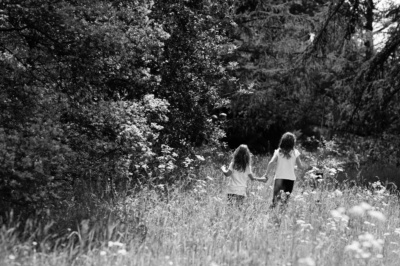 Sisters walk through a field of wildflowers.