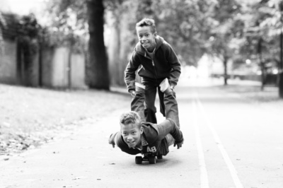 Skateboarding brothers roll down a hill together.