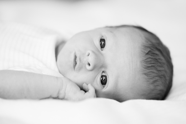 A sleepy newborn looks at the camera.