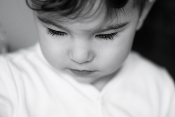 A small chid looks down, showing details of their eyelashes.