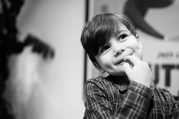 Black and white portrait of a smiling child in a checked shirt.