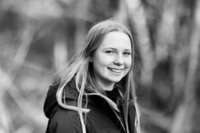 A smiling teenage headshot with trees in the background.